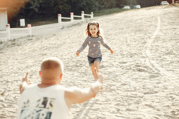 Family sitting on the sand. Father in a t-shirt. Cute little girl