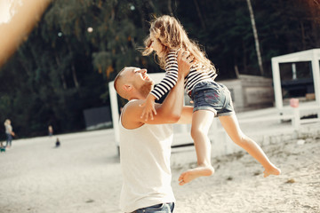 Family sitting on the sand. Father in a t-shirt. Cute little girl
