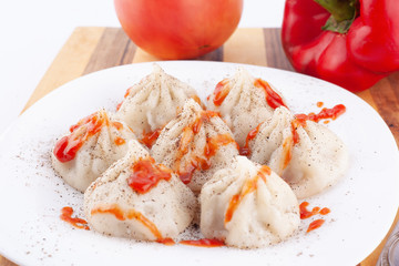 Traditional georgian food khinkali with ketchup and vegetables on white plate 