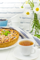 A Cup of tea with homemade honeysuckle pie and streisel on the table. Summer a delicious Breakfast of berry pie.