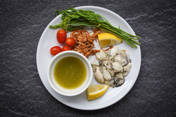 Fresh oysters served on plate and dark background - Oyster Salad with vegetable tomato lemon and herb  seafood sauce in the restaurant
