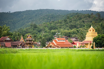 Fototapeta na wymiar Scenery view of green rice field with old temple in Thailand golden pagoda and mountain ancient temple beautiful landmark of buddhist Wat Sri Pho Chai at Na Haeo Loei Thailand naheaw