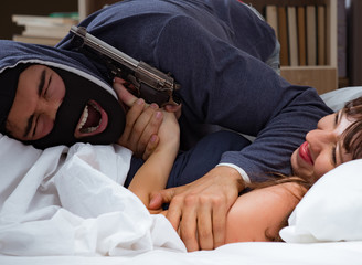 Burglar breaking into house at night to bedroom with sleeping wo