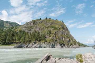 The confluence of two rivers. Two different rivers are connected into one. The river is of different colors. Mountain river of turquoise color. The mountain river is dark in color. Beautiful rivers