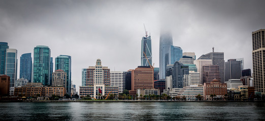 San Francisco skyline with low clouds covering the tip of some buildings seen from a ferry in color