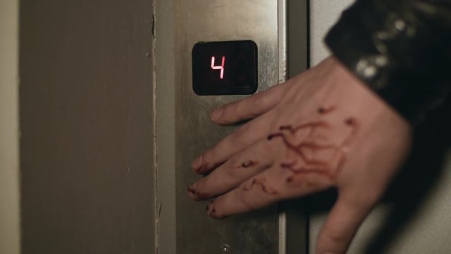 Wounded bleeding hand is pushing elevator button