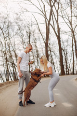 Beautiful couple in a park. Sportsman in a sportswear. Couple with a dog