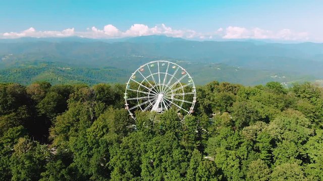 A ferris wheel spins on top of a mountain