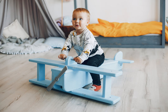 Cute little boy have fun in a room. Child playing at home with wooden airplane