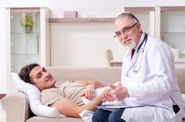 Fototapeta premium Old male doctor visiting young male patient