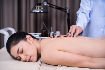 woman undergoing acupuncture treatment with electrical stimulator on back