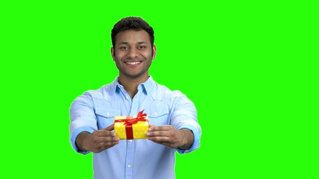 Handsome man giving gift box on green screen. Smiling guy in shirt offering present box standing on Alpha Channel background.