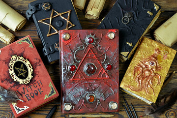 Pile of magical evil books with spells on witch table.