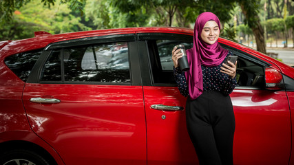 Muslim Female with her smartphone beside her car. Car insurance concept.