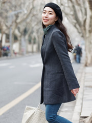 Beautiful Chinese young woman in suit and jeans walking and crossing road, smiling at camera with bag in hand, confident business woman, Outdoor fashion portrait of glamour stylish lady.