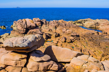 Seascape with huge pink granite boulders near Plumanach. The coast of pink granite is a unique...