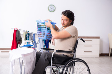 Young man in wheel-chair doing ironing at home