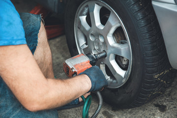 Fototapeta premium car mechanic screwing a car wheel
