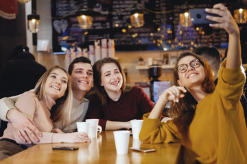 Five young handsome students sitting in a cafe.