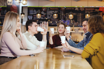 Five young handsome students sitting in a cafe.