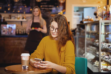 Young pretty woman and waitress in cafe.