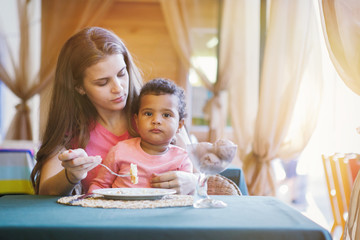 Cute black baby girl with mom in a summer cafe.