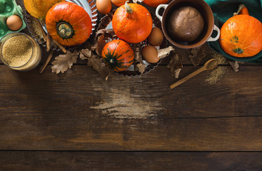 Raw ingredients for cooking pumpkin pie with dry autumn leaves on wooden background with copy space