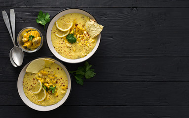 Sweet corn soup on cutting board on wooden dark background