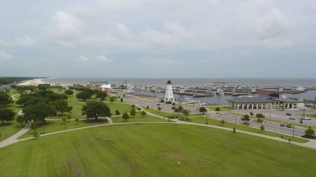 Aerial view of a lighthouse on the edge of a boat dock at a park on the edge of the ocean. Filmed in 4k 60fps and slowed to 24fps (23.976).