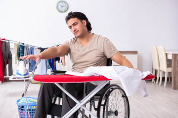 Young man in wheel-chair doing ironing at home
