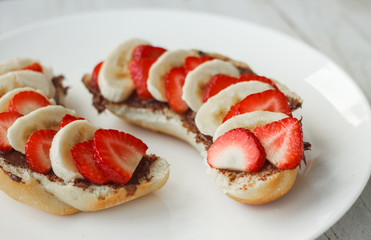 Delicious breakfast. Sandwich with chocolate paste, banana and strawberries.