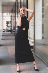 black evening womens dress on beautiful slender European model. Posing on street