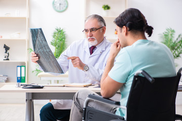 Obraz premium Male patient in wheel-chair visiting old doctor