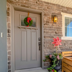 Square frame Porch of a home decorated with wooden chair potted plants wreath and doormat