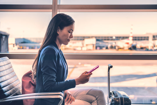 Airport Phone Travel Asian Businesswoman Using Mobile Smartphone In Business Class Lounge Waiting For Plane Flight Texting Sms Message. Technology And Travel People VIP Lifestyle.