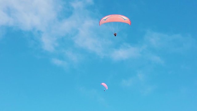 A slow motion shot of paragliders in the sky.