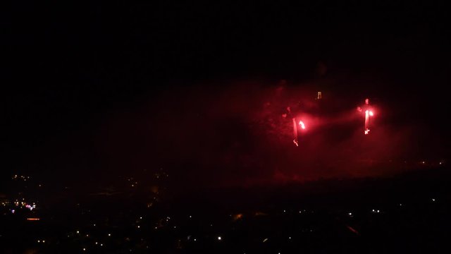 Celebration with red fireworks, over a mountain town, at night