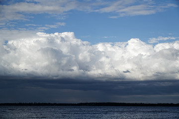 Storm cloud and lighthouse. Dramatic cloudscape texture. Dark heavy thunderstorm clouds before rain. Overcast rainy bad weather. Storm warning. Natural blue background of cumulonimbus