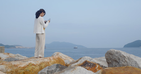Woman control a drone at the seaside