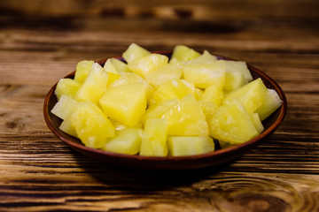 Ceramic plate with chopped canned pineapple on wooden table