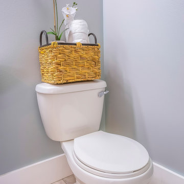 Square Frame Toilet At The Corner Of A Bathroom With A Rattan Basket On Top Of The Tank