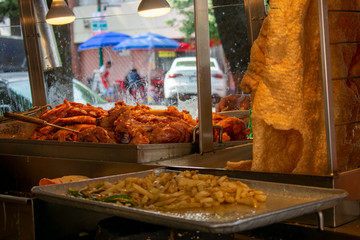 Vista interior de puesto de carnitas estilo Michoacán y chicharrón de cerdo, con parrilla friendo cebolla, con vista a la calle