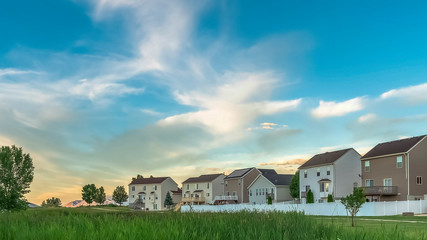 Panorama Expansive terrain covered with rich green grasses in front of family homes