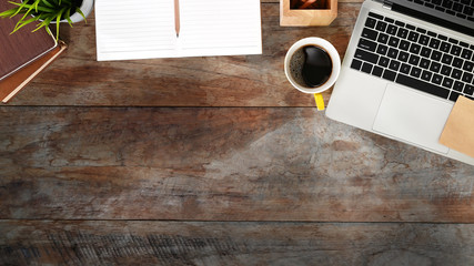 Top view workspace laptop, notebook, pencil and coffee on retro wood table.