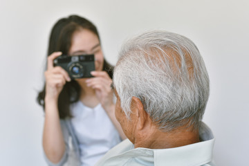 Happy family relationship, Asian daughter taking photo of old elderly father to keep good memory, Difference generations enjoy spending time and having activity together.