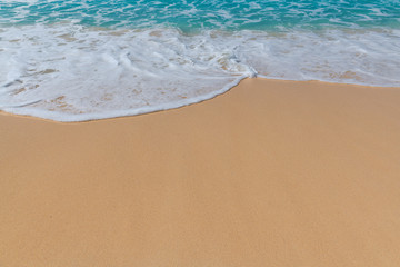 Sandy beach background with ocean wave white foam.