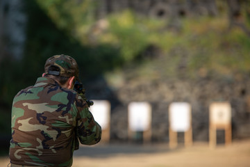 a guy in army clothes shoots at a target with a submachine gun