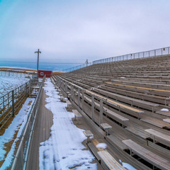 Square Row of tiered benches on a sports arena under a cloudy sky in winter