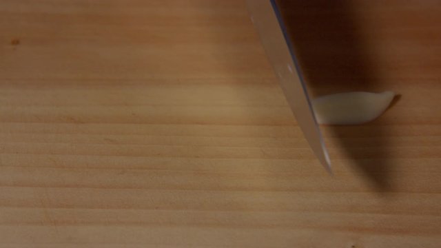 a Japanese female chef slicing the garlic clove (ingredients of Japanese style fried chicken) at her home kitchen, Tokyo, Japan. June 2019. Camera fixed, extreme close-up, high angle
