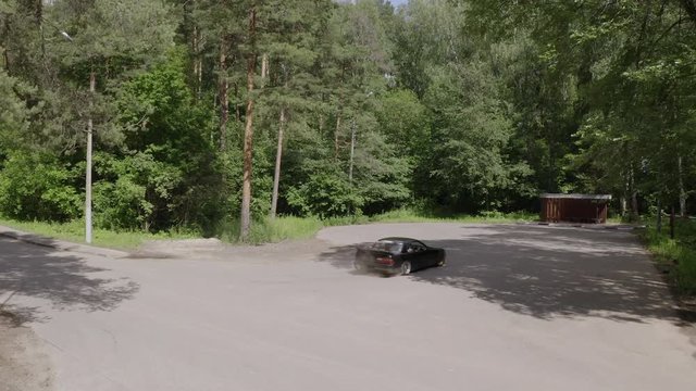 Aerial view japanese car drifting on asphalt road in countryside. Racing car driving with driftage on countryside road. Japanese car turning with drift drone view